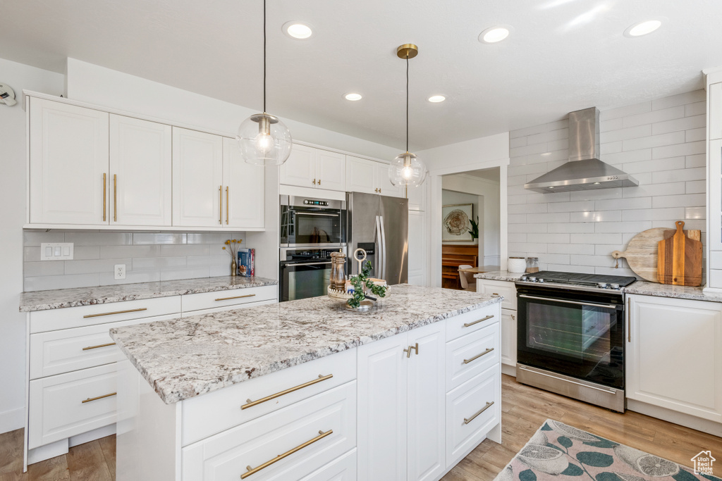 Kitchen featuring appliances with stainless steel finishes, wall chimney range hood, backsplash, light wood finished floors, and recessed lighting