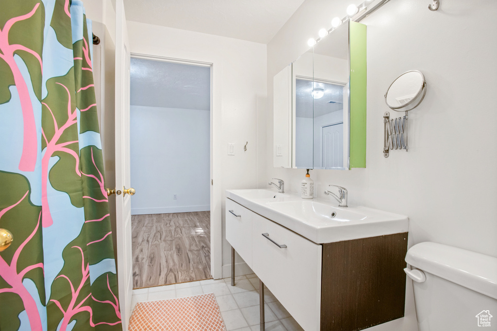 Full bathroom featuring toilet, double vanity, and tile patterned floors