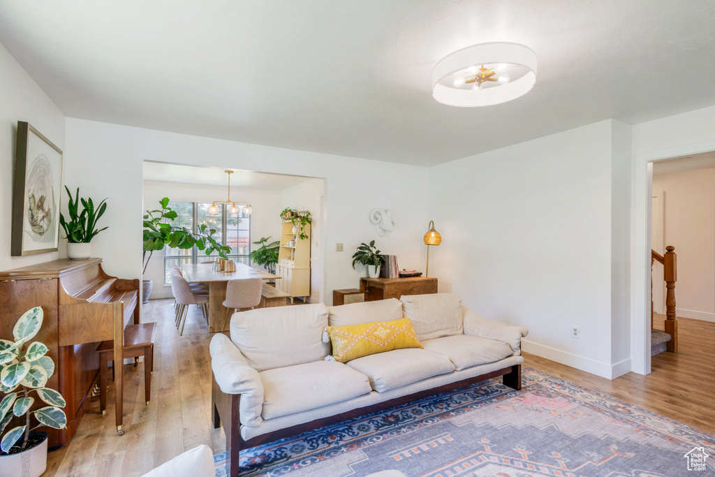 Living area featuring light wood finished floors, a chandelier, and baseboards