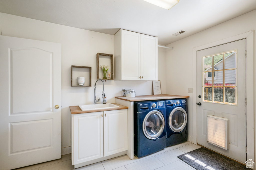 Laundry room featuring cabinet space, washing machine and dryer, and radiator