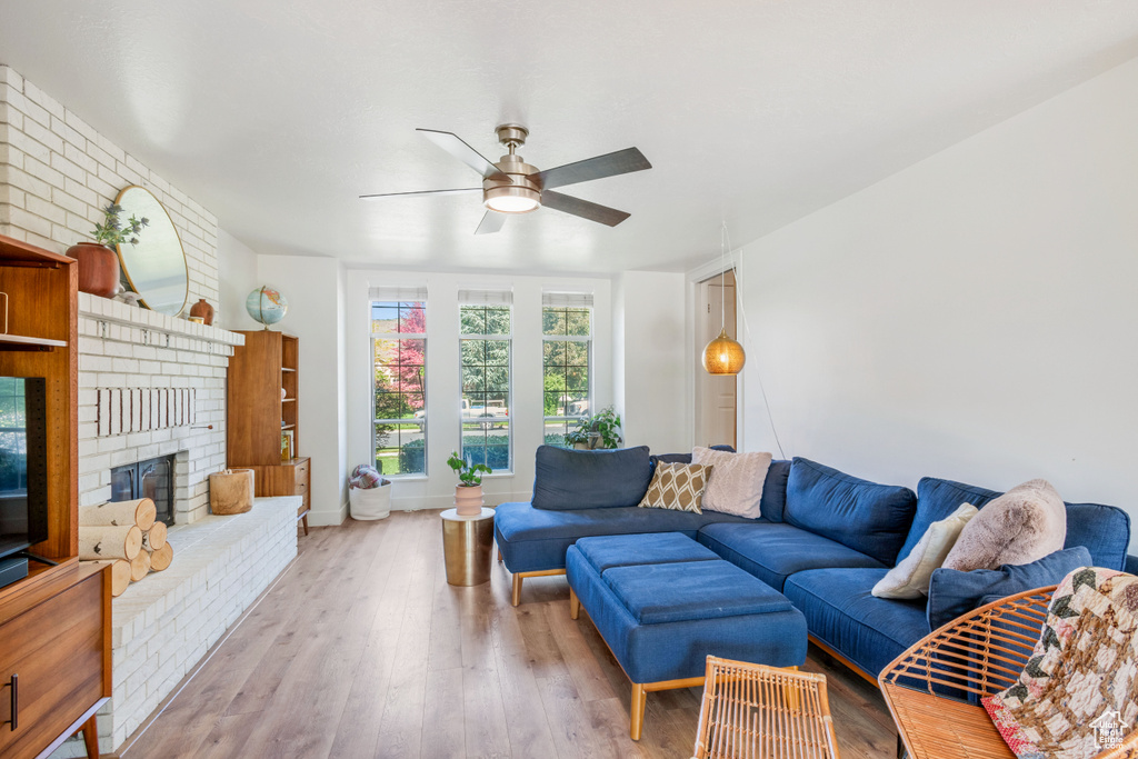 Living room featuring a ceiling fan, wood finished floors, and a fireplace