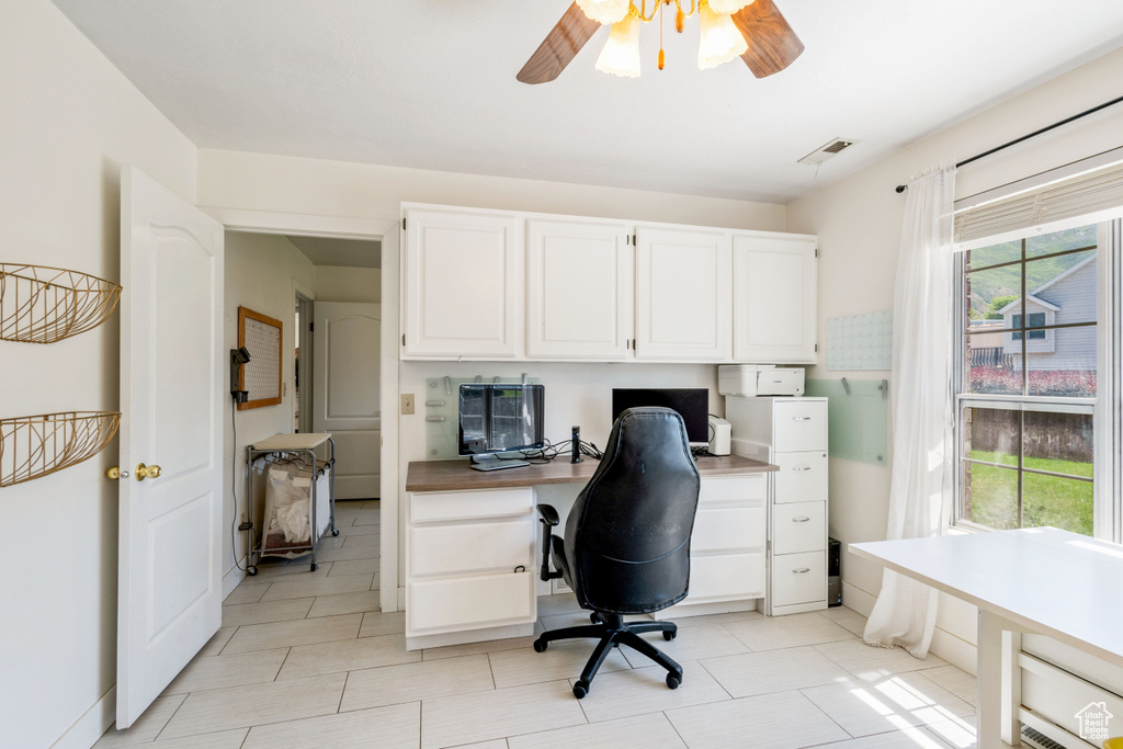 Home office with ceiling fan, built in desk, and light tile patterned floors