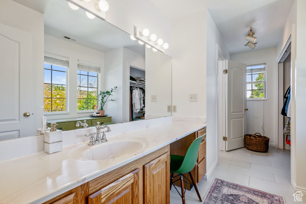 Bathroom with vanity, a walk in closet, tile patterned floors, and baseboards