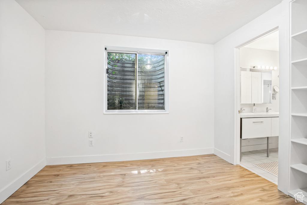 Unfurnished room with light wood finished floors, baseboards, and a sink