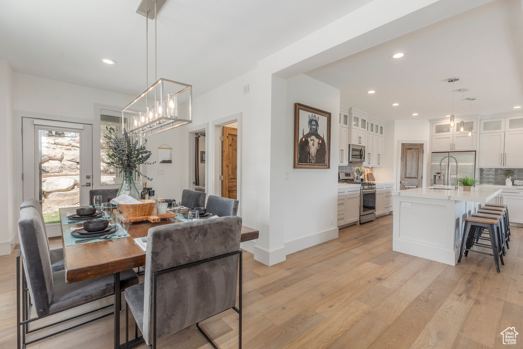 Dining area with light wood-style flooring, recessed lighting, baseboards, and a chandelier