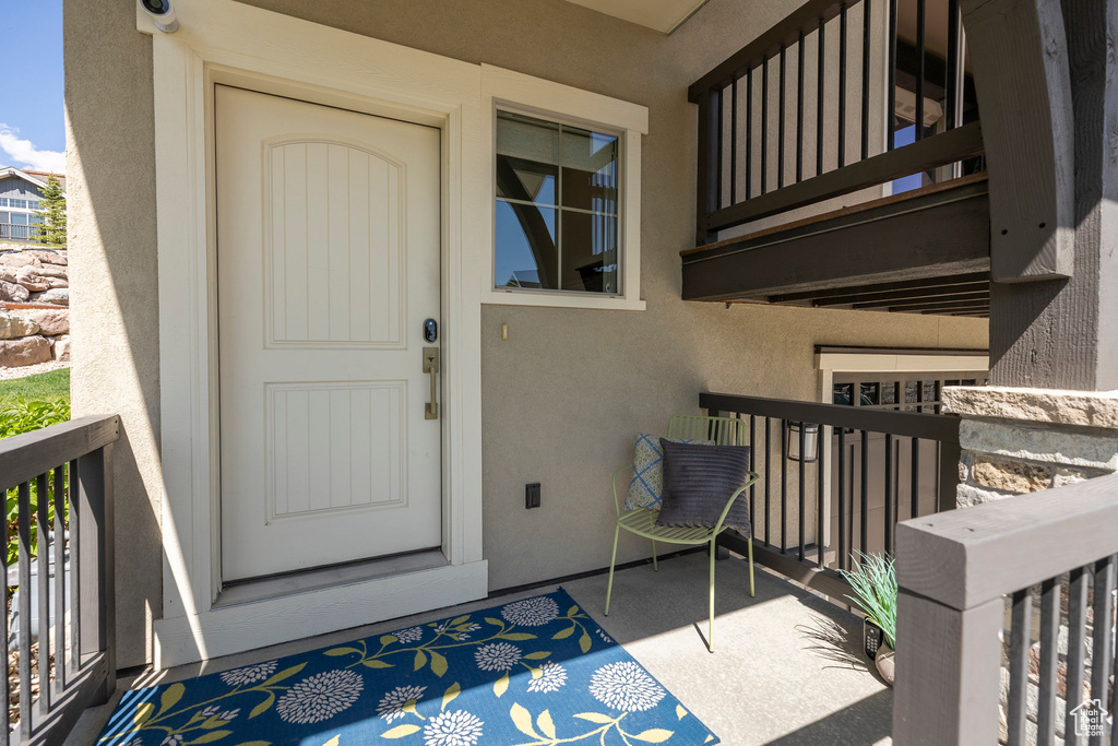 View of exterior entry with a balcony and stucco siding