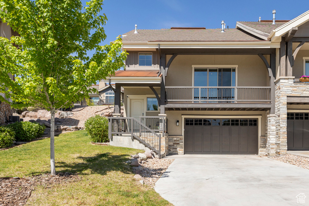 View of front of house featuring stone siding, stucco siding, an attached garage, a front yard, and driveway