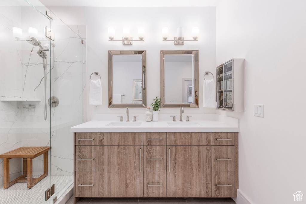 Full bath with a marble finish shower and double vanity