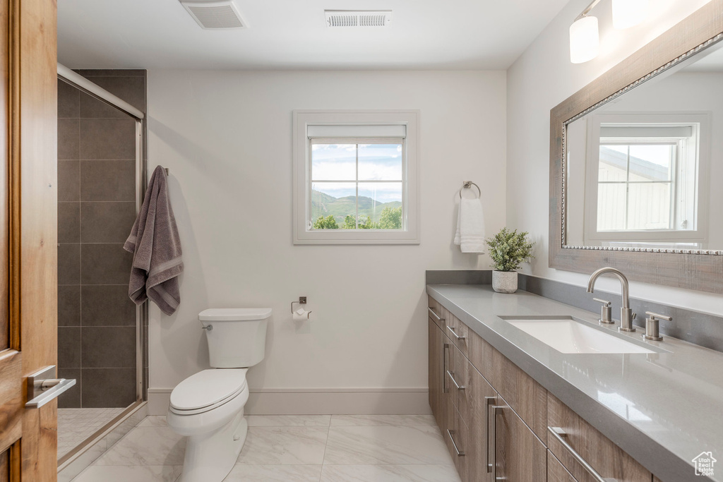 Full bathroom featuring toilet, marble look tiles, vanity, a shower stall, and baseboards