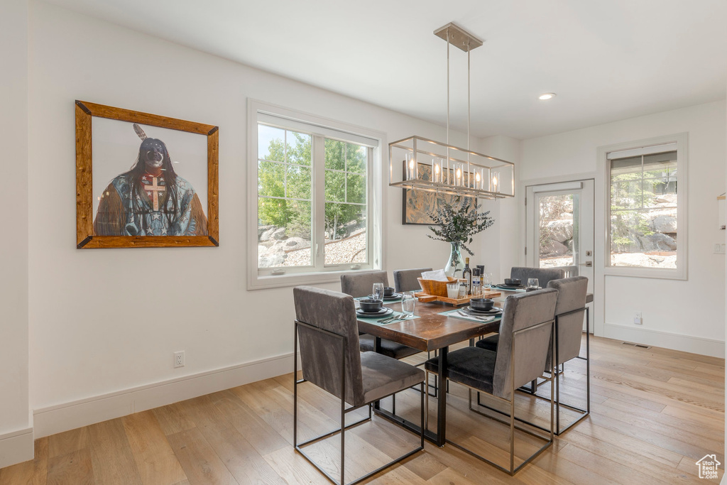 Dining room with plenty of natural light, a chandelier, light wood-style flooring, baseboards, and recessed lighting