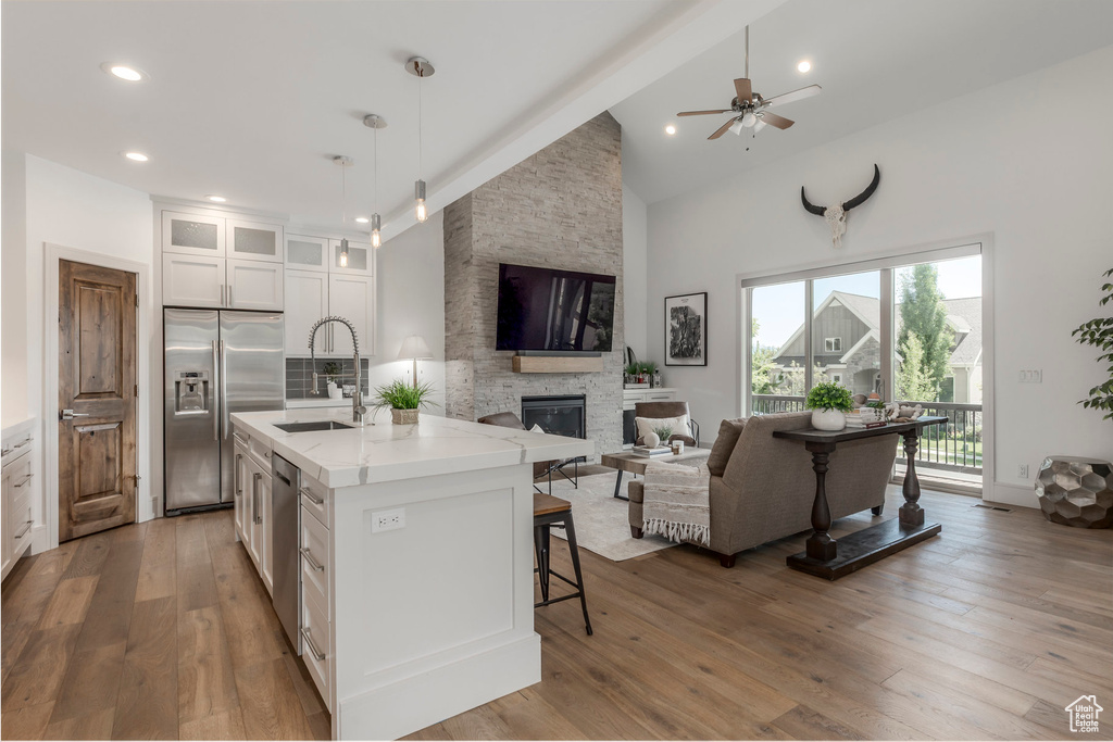 Kitchen featuring appliances with stainless steel finishes, a sink, a fireplace, open floor plan, and high vaulted ceiling