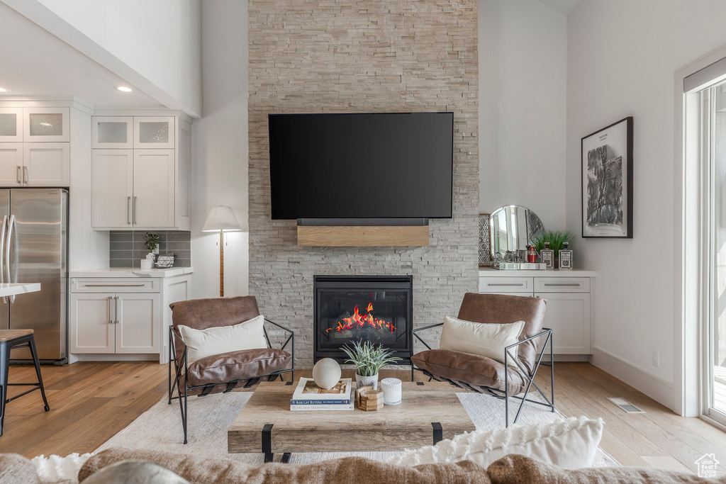 Living room with a fireplace, a high ceiling, light wood-type flooring, and baseboards