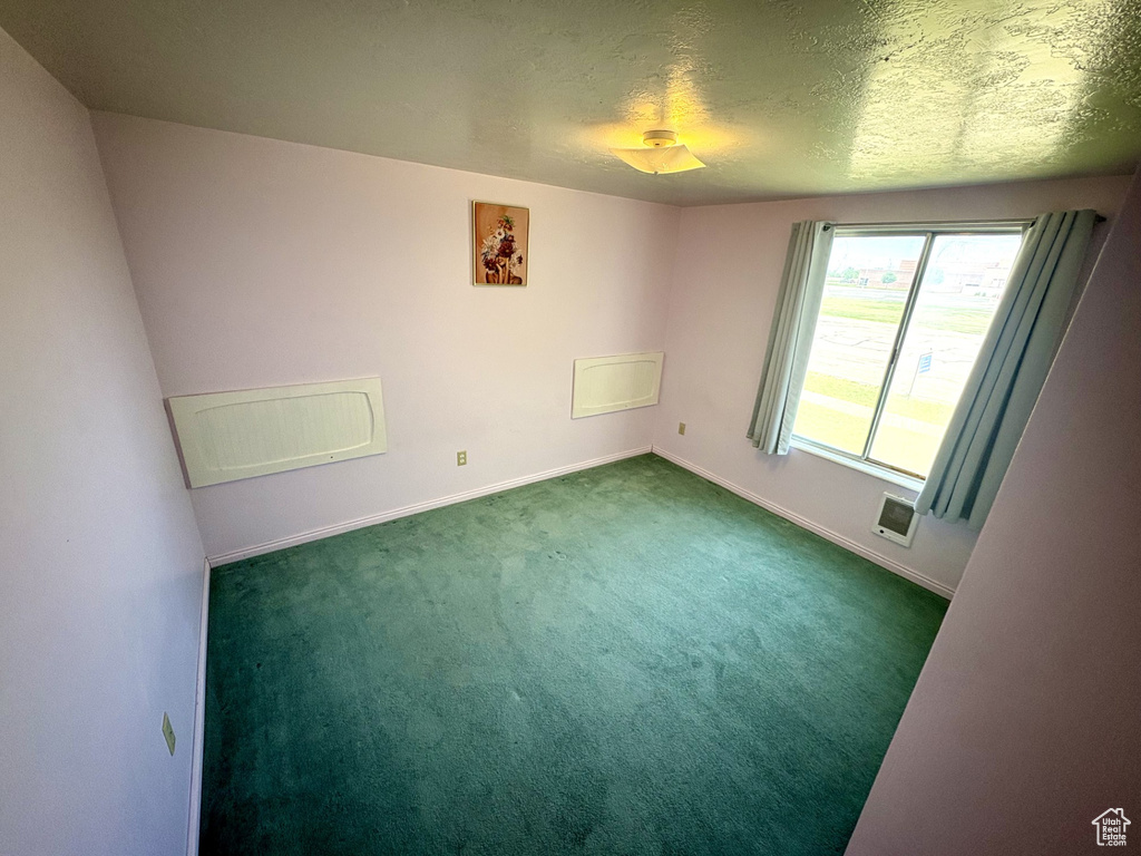 Carpeted spare room featuring baseboards and a textured ceiling