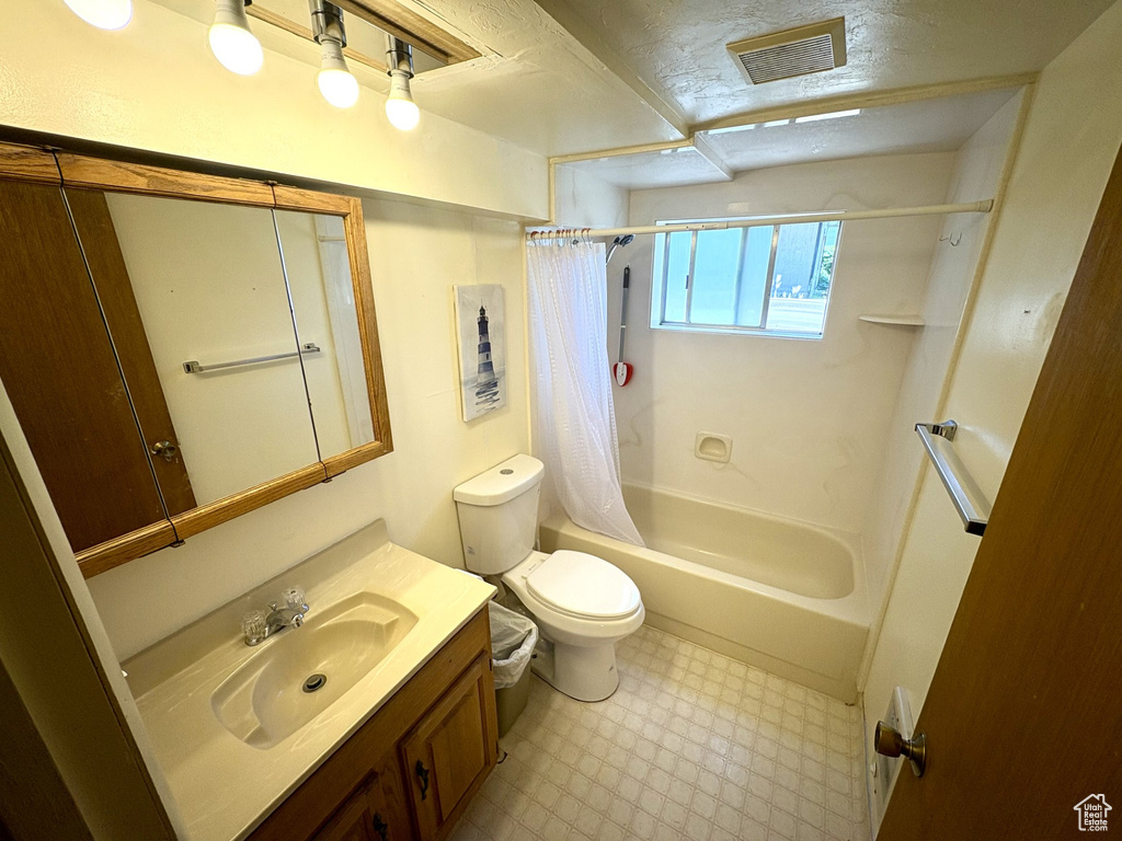 Full bath with tile patterned floors, toilet, vanity, and shower / bath combo