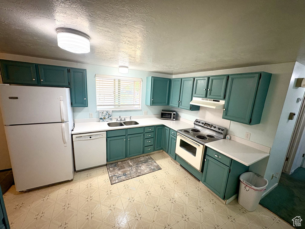 Kitchen featuring white appliances, light flooring, a sink, under cabinet range hood, and green cabinets