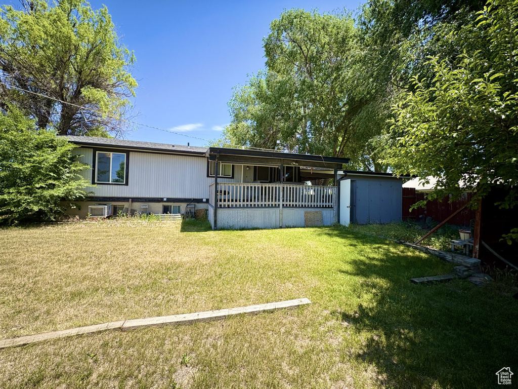 Rear view of property with central air condition unit, a lawn, and a porch