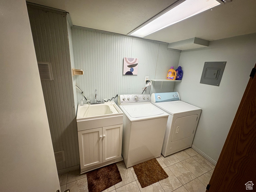 Washroom with separate washer and dryer, electric panel, light tile patterned floors, cabinet space, and baseboards