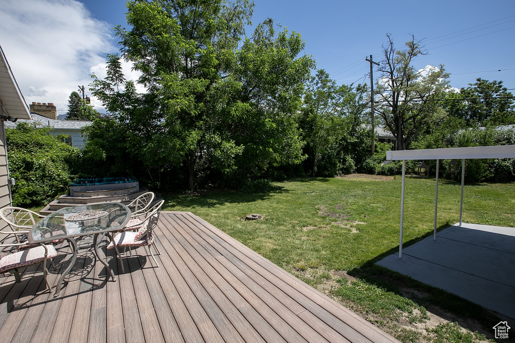 Wooden deck featuring outdoor dining area and a lawn