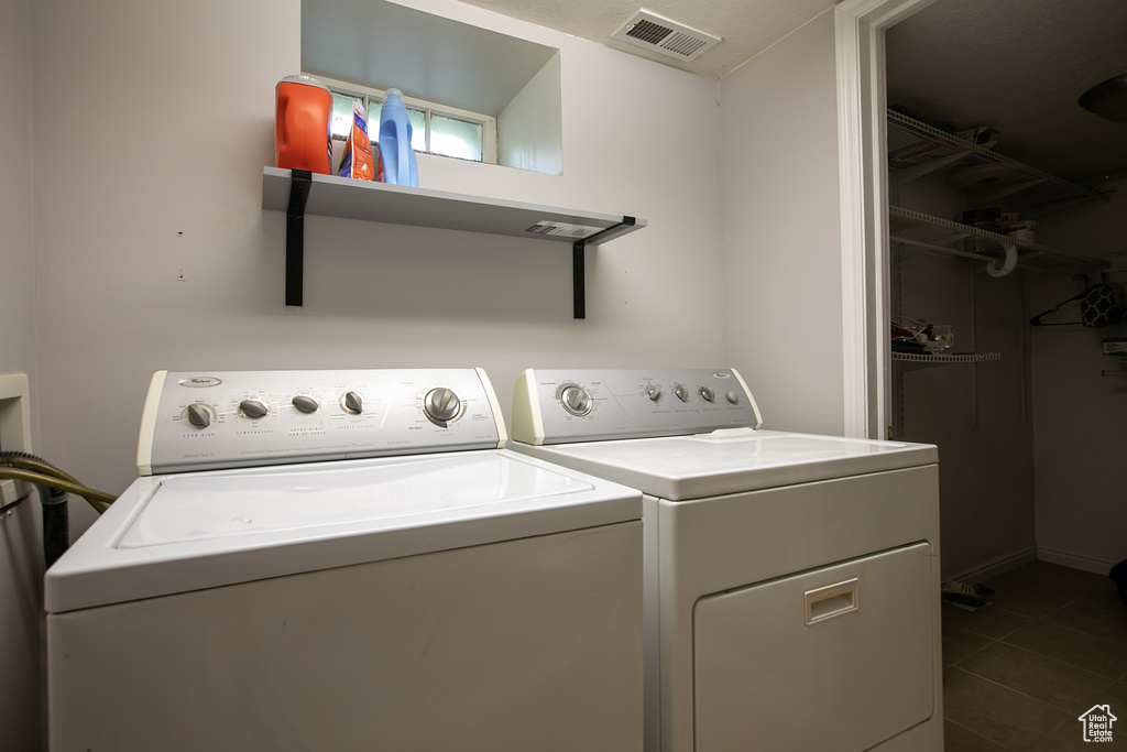 Laundry room with washing machine and clothes dryer and dark tile patterned flooring