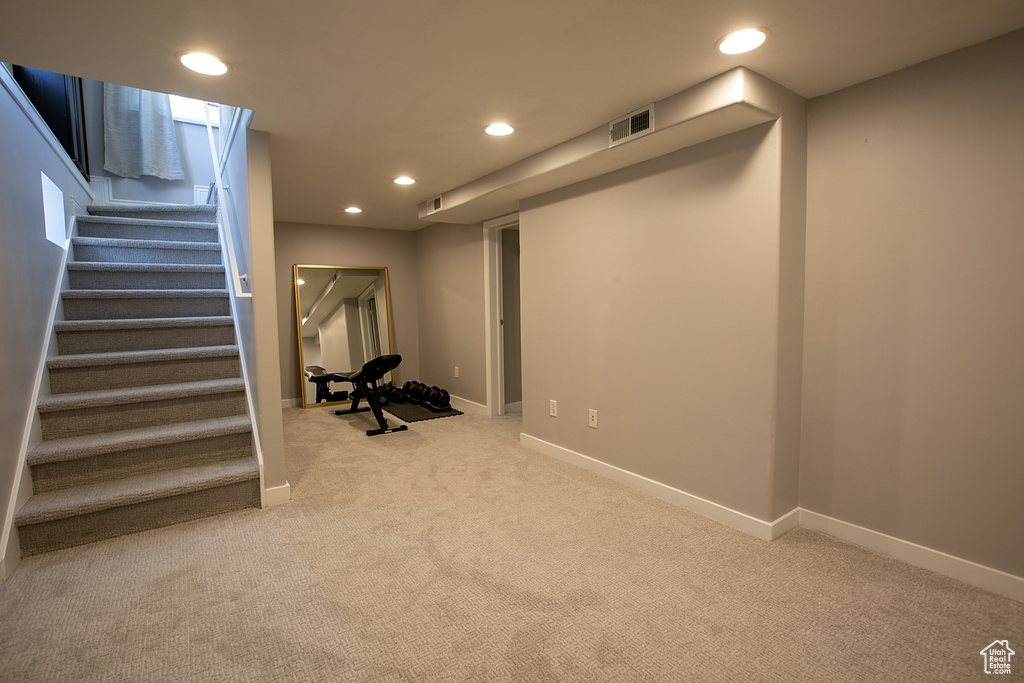 Finished basement featuring light colored carpet, recessed lighting, stairway, and baseboards