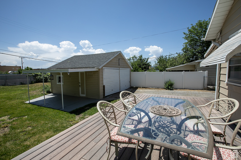 Wooden terrace featuring an outdoor structure, a patio area, and a garage