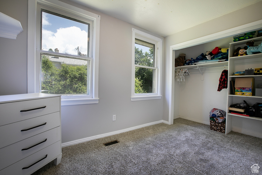 Carpeted bedroom with multiple windows, a closet, and baseboards