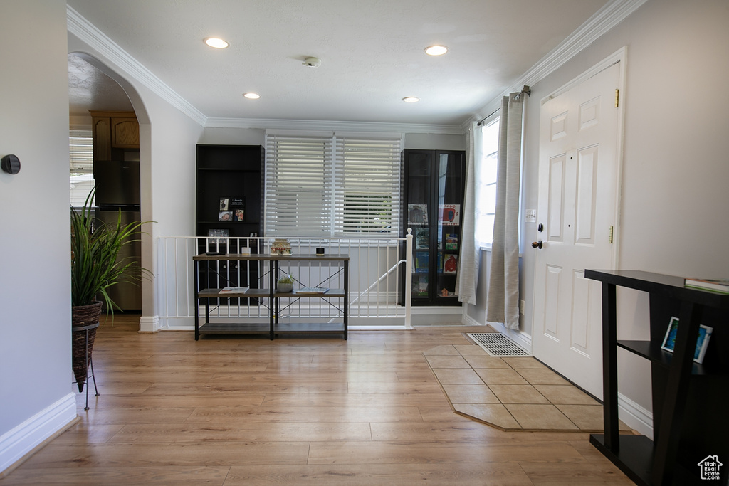 Entrance foyer with wood finished floors, crown molding, arched walkways, recessed lighting, and baseboards