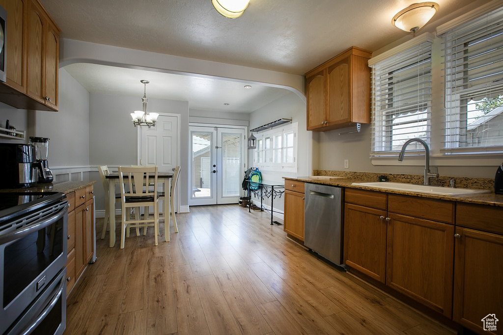 Kitchen featuring stainless steel appliances, a sink, arched walkways, and brown cabinetry