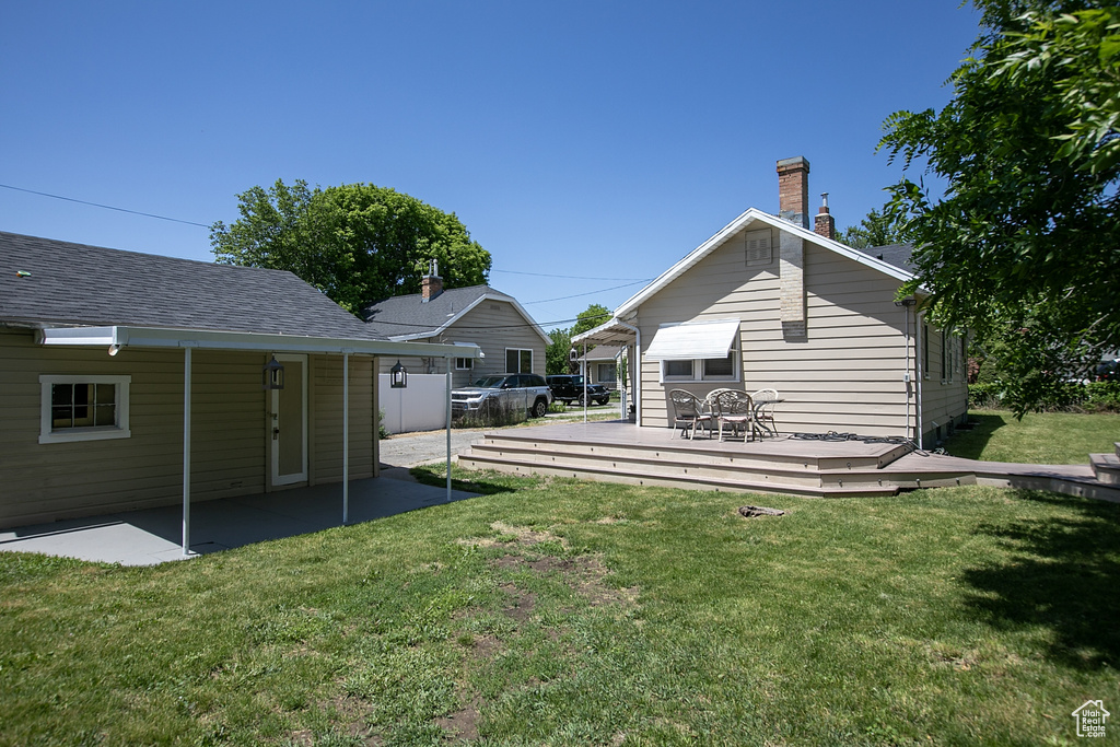 Back of house featuring a deck, a lawn, and a chimney