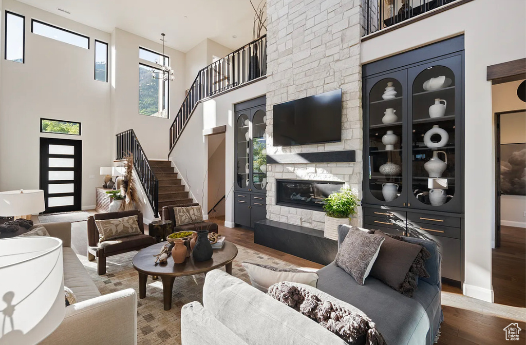 Living room featuring stairway, wood finished floors, a fireplace, baseboards, and a high ceiling
