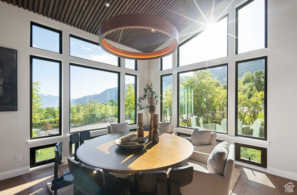 Dining area with baseboards, wood finished floors, a mountain view, and a towering ceiling