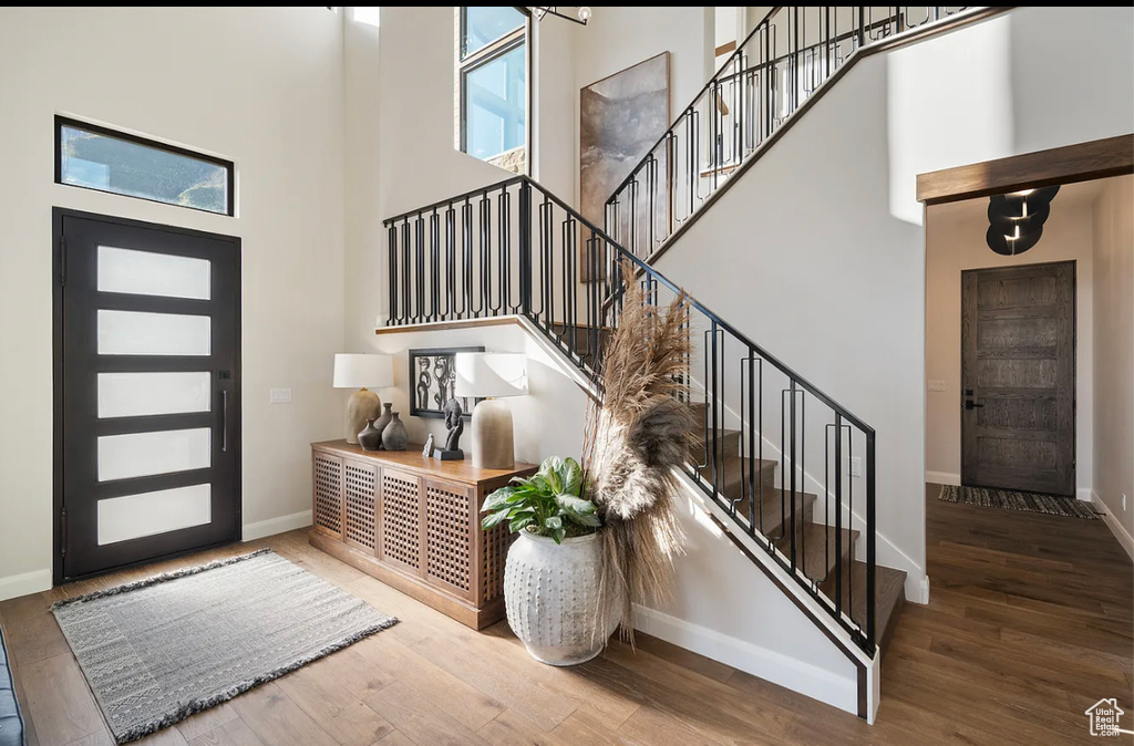 Foyer entrance with a towering ceiling, baseboards, wood finished floors, and stairs