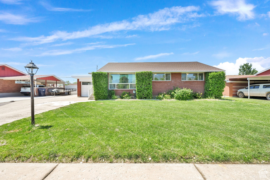 Single story home with a front yard, concrete driveway, a garage, and brick siding
