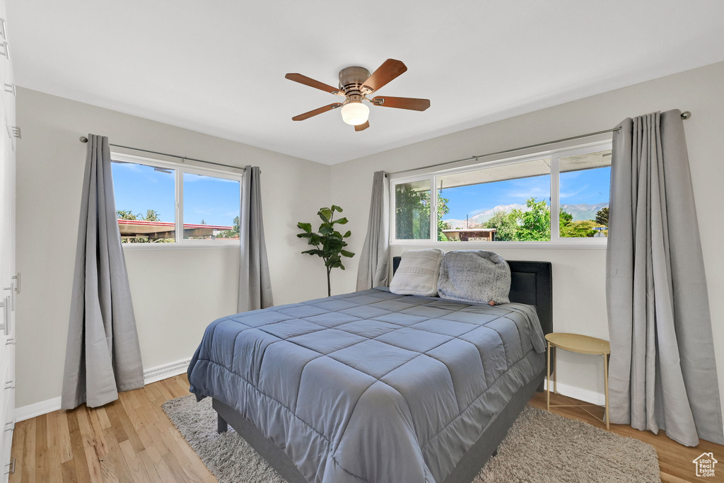 Bedroom featuring baseboards, light wood-type flooring, and a ceiling fan