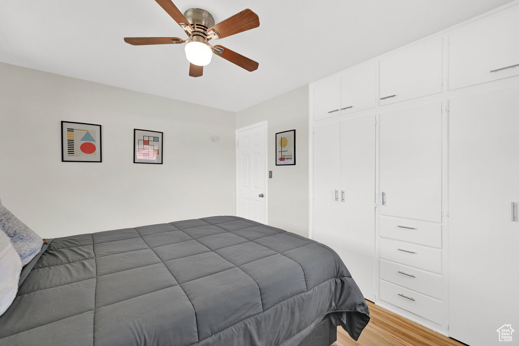 Bedroom with light wood-style floors, ceiling fan, and a closet