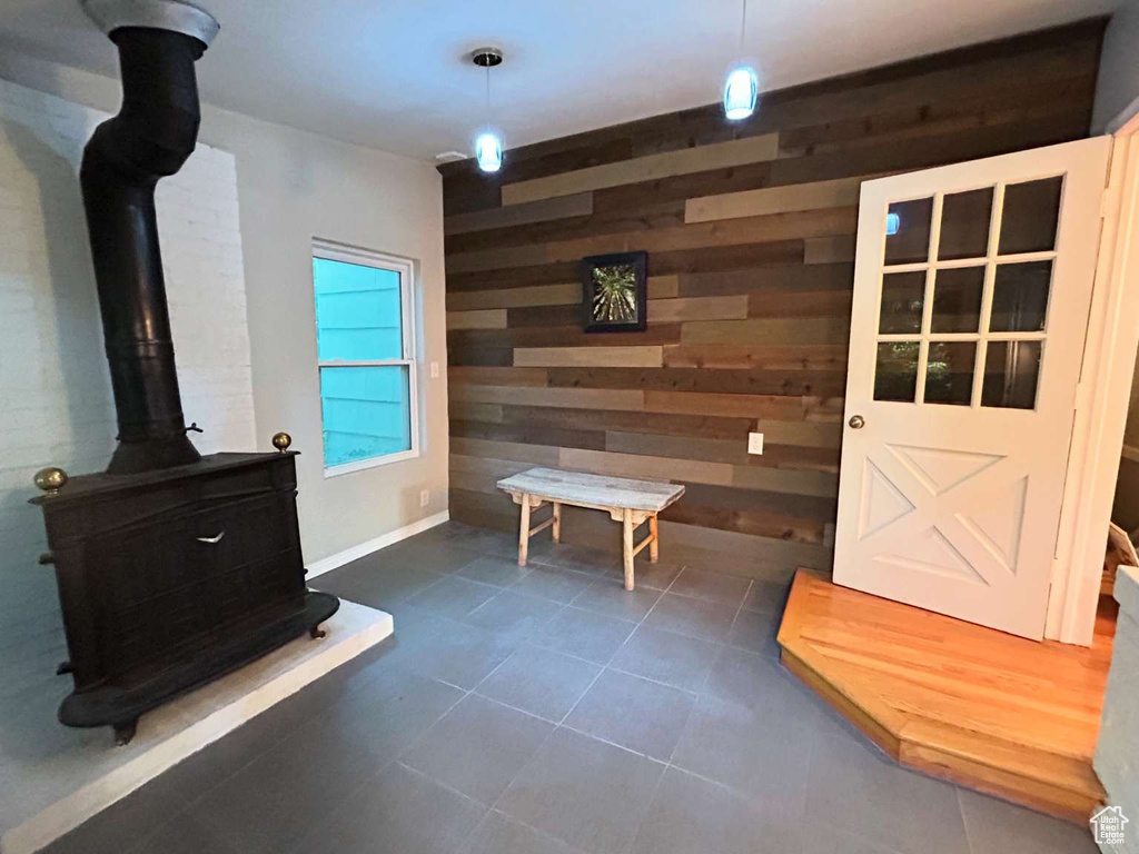 Mudroom with a wood stove, dark tile patterned floors, and wooden walls