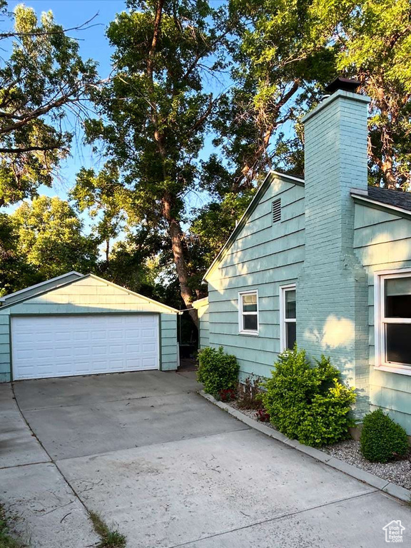 View of home's exterior featuring a garage, a chimney, and an outdoor structure