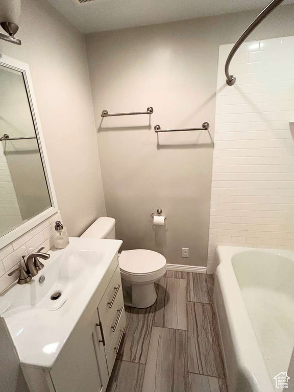 Bathroom featuring vanity, toilet, baseboards, and shower / tub combination