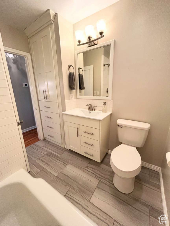 Full bathroom with toilet, vanity, a chandelier, and decorative backsplash