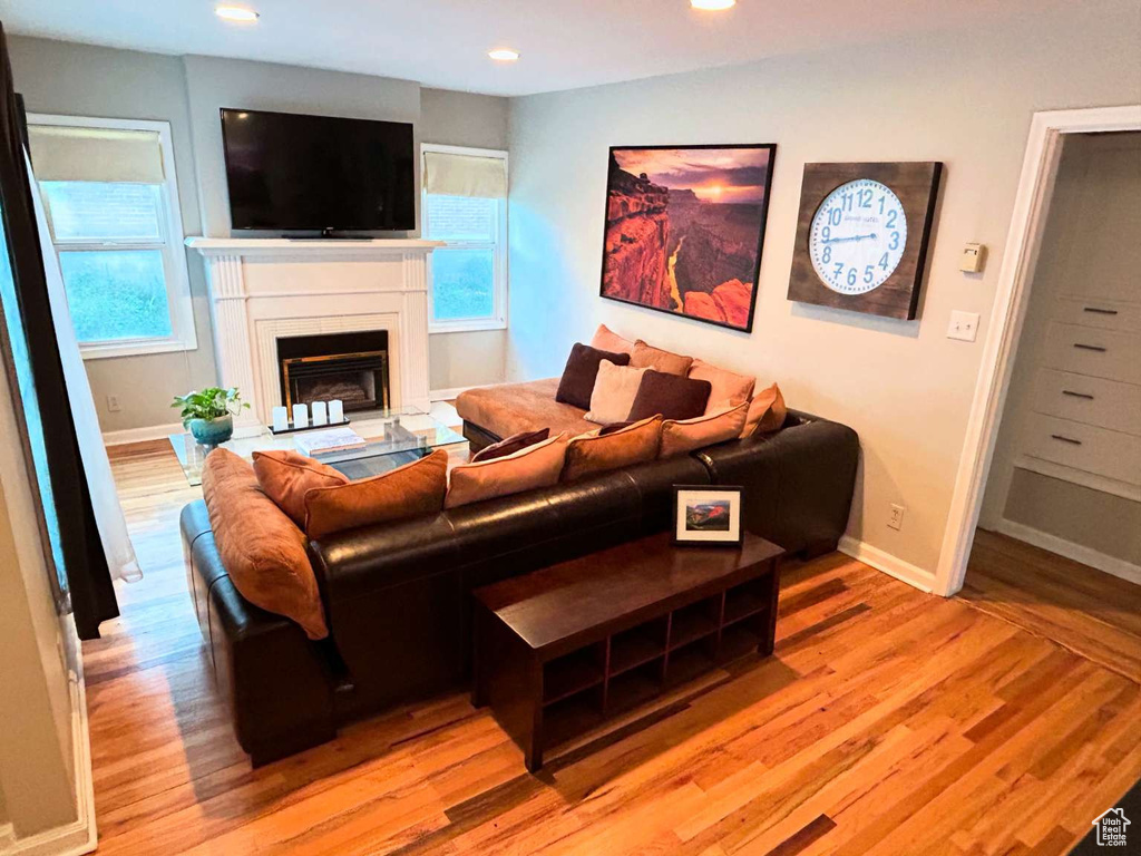 Living room featuring light wood finished floors, baseboards, recessed lighting, and a glass covered fireplace
