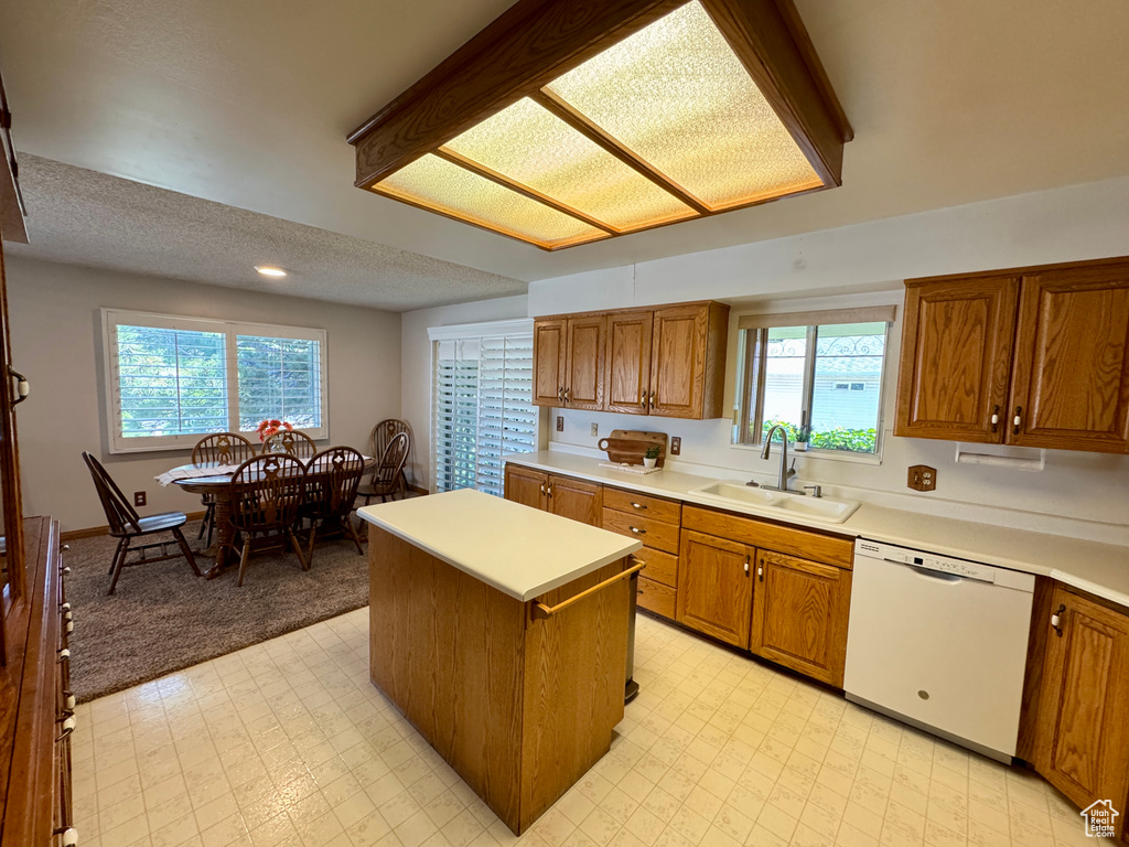 Kitchen featuring dishwasher, a sink, brown cabinetry, a textured ceiling, and recessed lighting