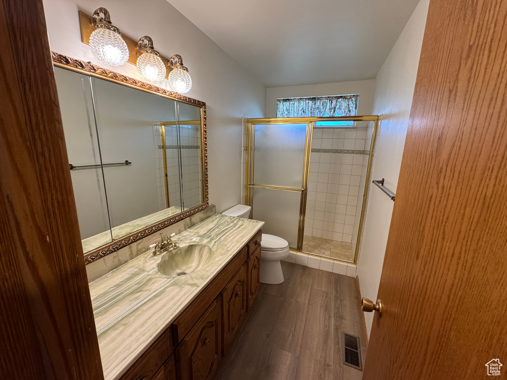 Bathroom featuring toilet, wood finished floors, vanity, and a shower stall