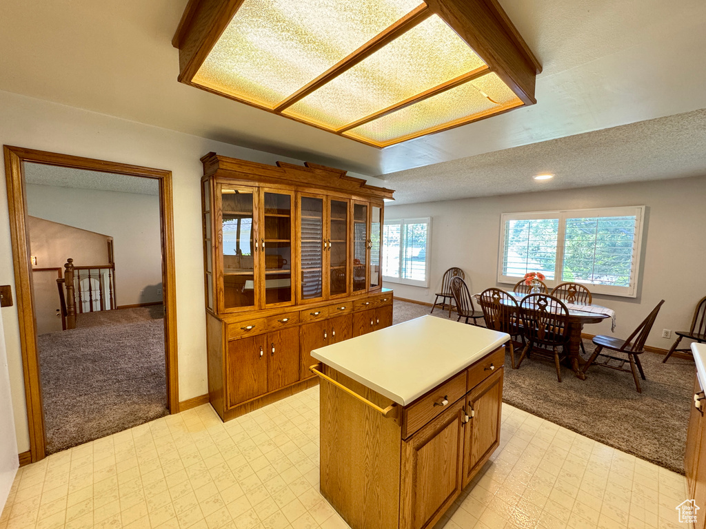 Kitchen with light colored carpet, brown cabinetry, and baseboards