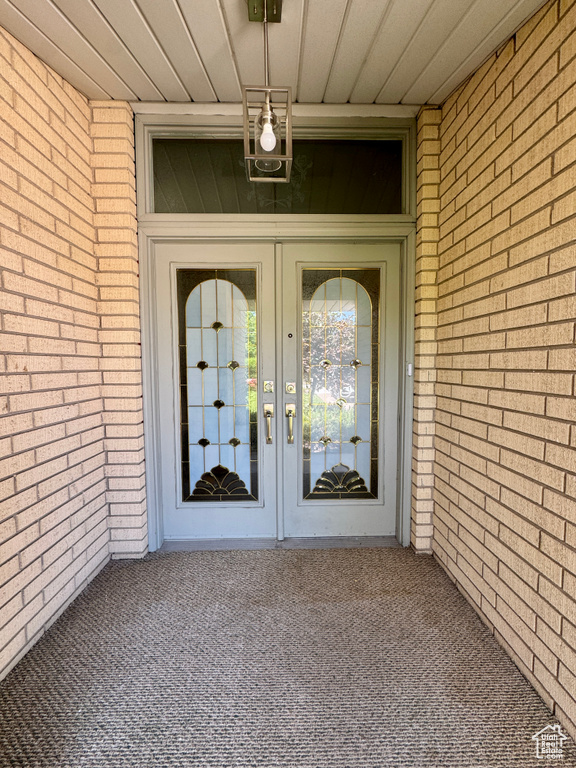 View of exterior entry featuring brick siding and french doors