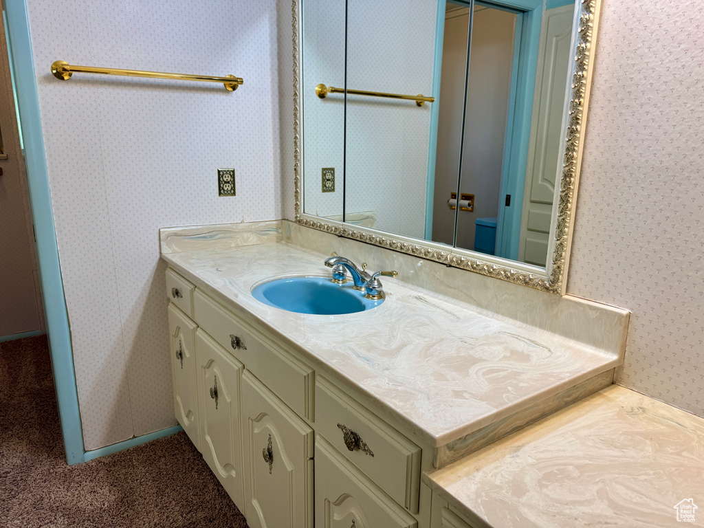 Bathroom with wallpapered walls, vanity, and toilet