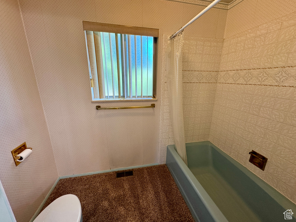 Bathroom with toilet and shower / tub combo with curtain