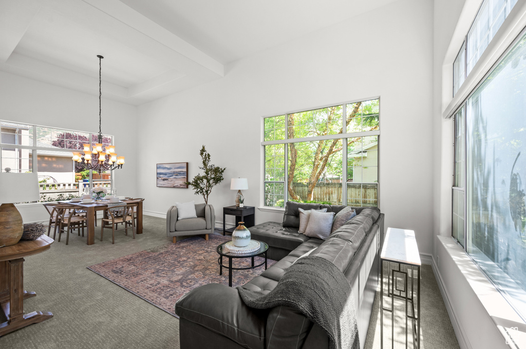 Carpeted living room featuring healthy amount of natural light, a chandelier, and a towering ceiling