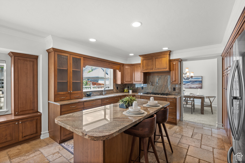 Kitchen featuring stone tile flooring, brown cabinets, a sink, gas stovetop, and recessed lighting