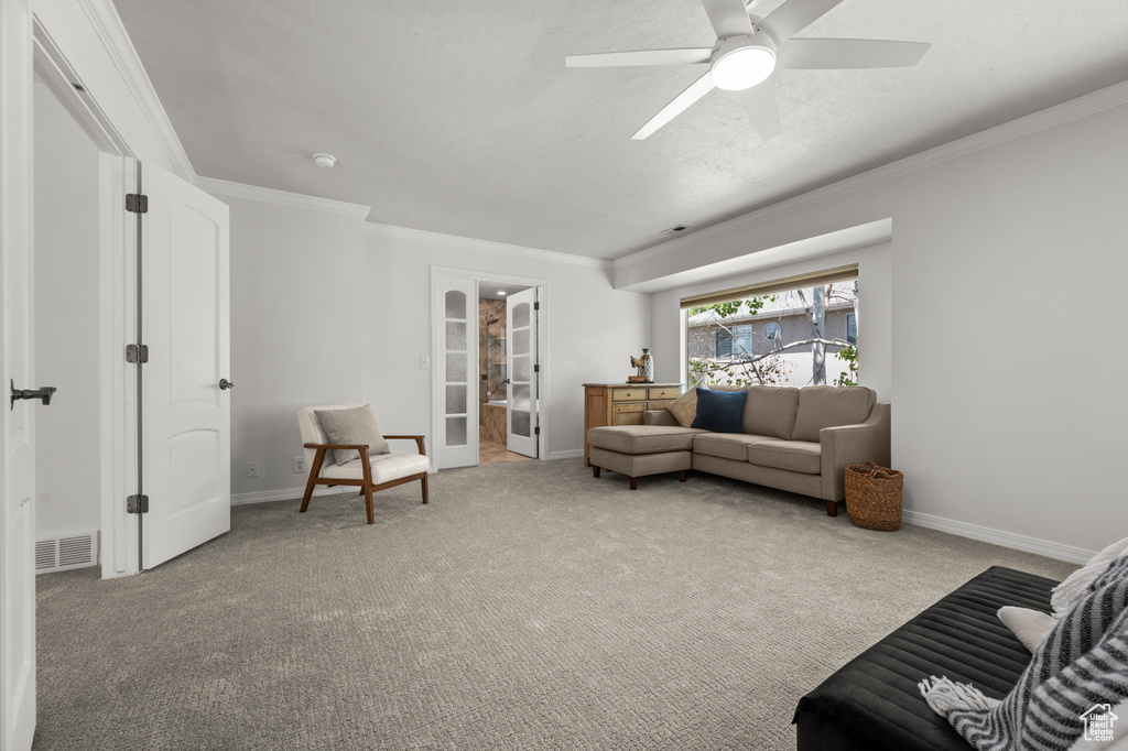 Carpeted living area with ornamental molding, baseboards, and ceiling fan