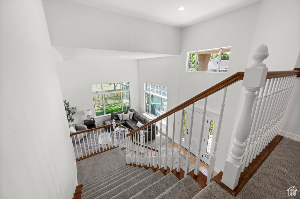 Staircase featuring plenty of natural light, wood finished floors, baseboards, recessed lighting, and a towering ceiling